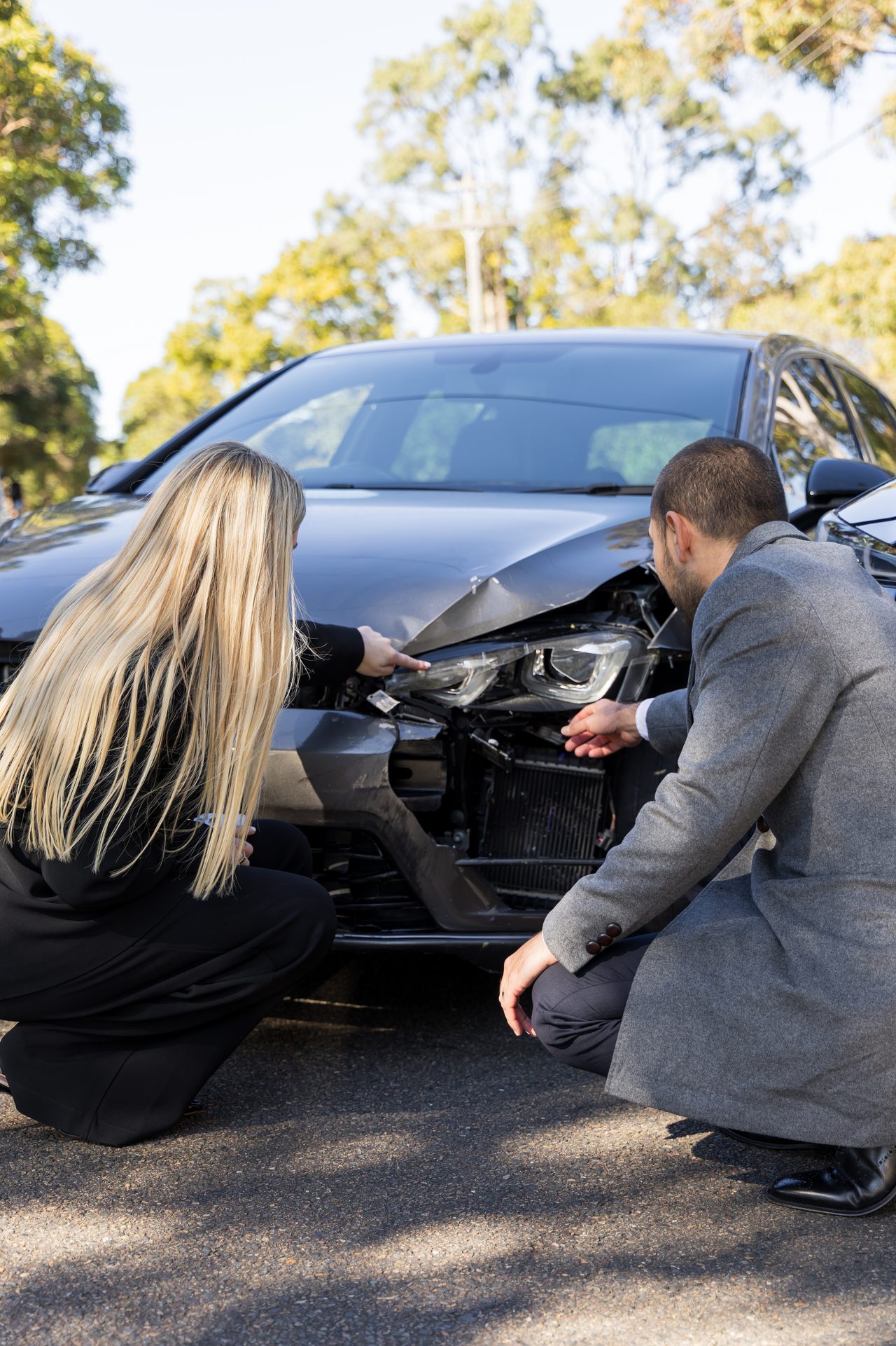 Two people inspecting car accident damage